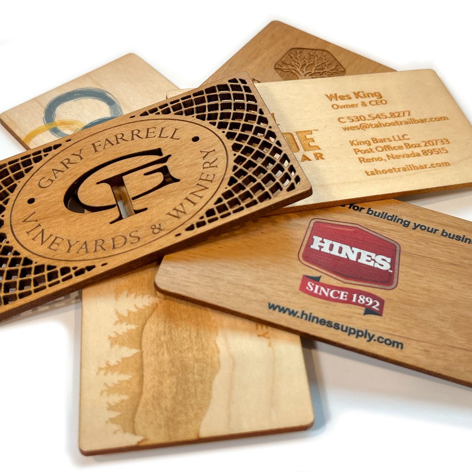 An assorted stack of laser cut maple and alder business cards that have been either laser engraved ot UV printed